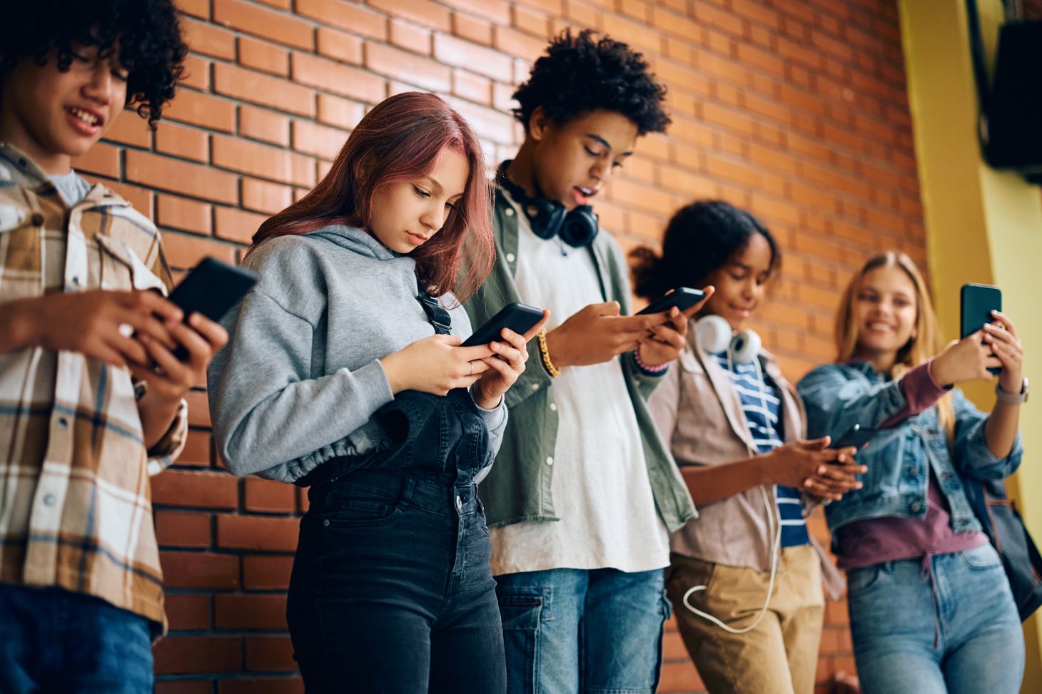 A group of teenagers all focused on the screens in their hands - digital addiction